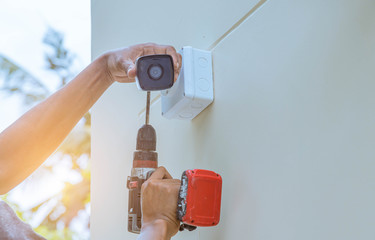 Technician installing IP CCTV camera and water proof box to protect camera is home security system...