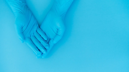 hands gesture of doctor wearing blue gloves on blue background, heart shape sign for love