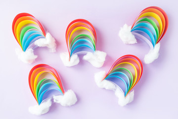 A small rainbow of colored paper with clouds of snow, creativity with their hands on a light background. DIY