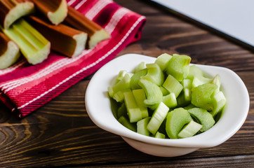 Rhubarb on wooden table. Fresh rhubarb on white bowl. 