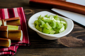 Rhubarb on wooden table. Fresh rhubarb on white bowl.