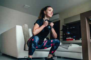 giovane bella ragazza fa sport a casa eseguendo esercizi a corpo libero. Smart gym e distanza sociale durante la pandemia 