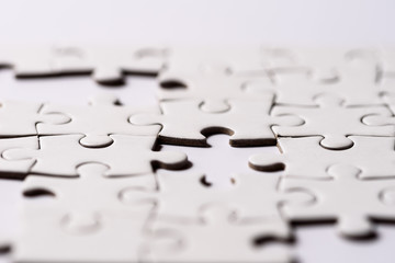need to find solutions.
Close up on blank, white puzzle. One piece is laking