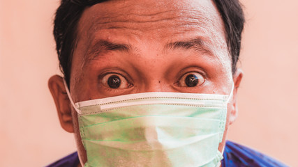 Asian man wearing face mask shows expression. The concept of people having to wear masks in public during  the COVID-19 pandemic or coronavirus disease crisis.