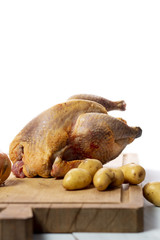 Uncooked whole chicken ready for cooking with vegetables on a chopping board. White background.