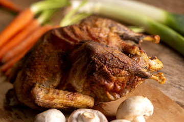 Crispy roasted chicken and leeks, carrots and mushrooms, on a chopping board.