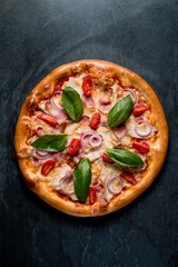 Italian pizza with cheese bacon tomatoes basil on black background top
