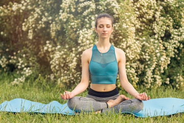 Young Caucasian woman meditating in Lotus position. Yoga in the Park.