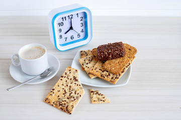 Cup of coffee with cereal cookies on a white wooden table. Breakfast time.