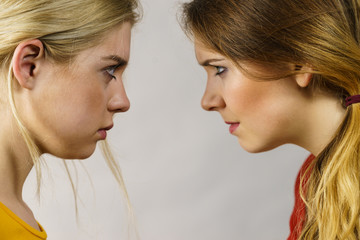 Two girls looking serious at each other.
