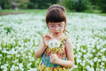 little girl playing with dandelions in the field. springtime