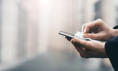 Smartphone screen disinfection using wet wipes and sanitizer. Coronavirus Covid 19 pandemic worldwide. Men's hands wipe the phone