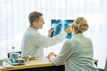 Obraz premium The patient wears a surgical mask, sitting Listening to medical advice from doctors with Lung X-ray Film and check up coronavirus covid19 disease at the hospital.Healthcare concept.