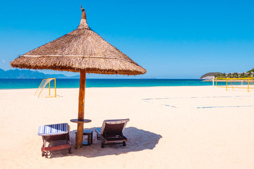 tropical beach with umbrella and chairs. Football field on background