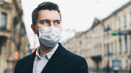 Quarantine in Europe in 2020. Prevention of coronavirus outbreak. Close up portrait of young european man wearing a mask in the city street. Prevent pollution and disease concept