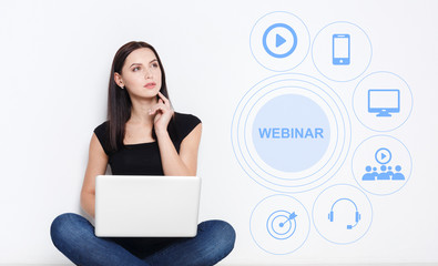 Thoughtful young girl using laptop for remote learning, word WEBINAR and educational icons on screen, collage