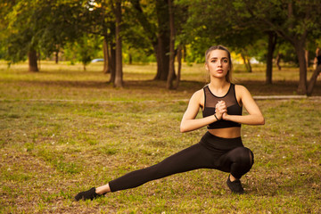 A young woman makes stretching legs in the Park. Does squats