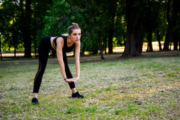 A young woman makes a warm-up in the Park. Makes bending and stretching