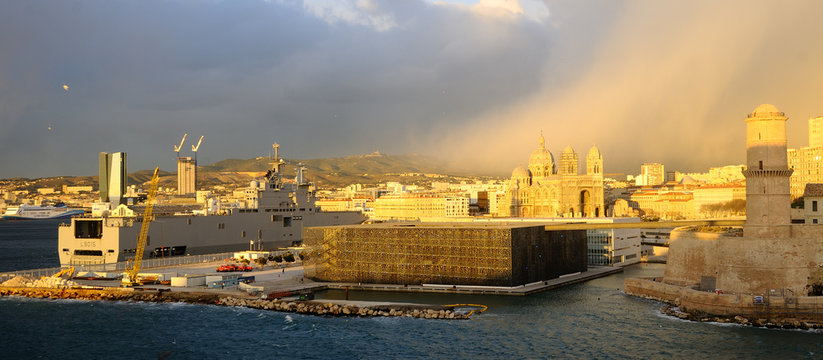 Jeux de lumi&egrave;res au coucher de soleil &agrave; Marseille : vue de l'esplanade du J4, du MUCEM et de la cath&eacute;drale, en pr&eacute;sence du b&acirc;timent de projection et de combat "Dixmude" de la marine nationale