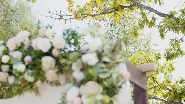Yellowed autumn dried oak branch against the background of a wooden wedding arch decorated with flowers