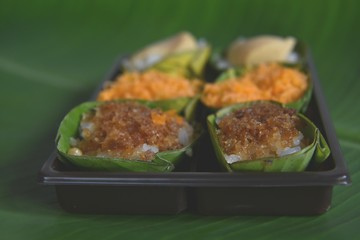 Delicious Thai desserts made from coconut cream rice in green banana leaves.