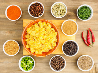 Raw pasta in a bamboo bowl and spice set: red chili pepper, masala, black pepper, cumin, fenugreek, cloves, green onion, fennel