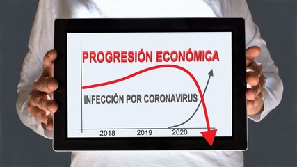 Male hands holding a digital tablet screen showing curves of progression of coronavirus infection and economy progression from 2018 to 2020. Translation: economic progression, coronavirus infection