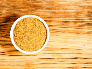 Spice masala powder in white bowl on brown wood background with copy space