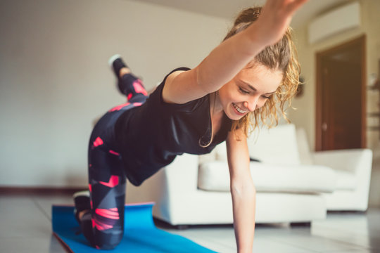 Giovane bella ragazza realizza esercizi fisici a casa. Esercizi funzionali a corpo libero nel salotto di casa © filippo