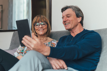 Coppia di europei di mezza et&agrave; realizza una video chiamata con la famiglia. Tablet, laptop, smartphone. Distanza sociale e tecnologia 