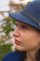 Stylish young lady on the street walks in spring in blue coat and cap.