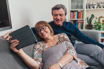 Coppia di europei di mezza età realizza una video chiamata con la famiglia. Tablet, laptop,...