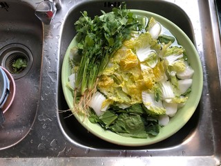 Preparing food for healthy food concept, fresh vegetables soaking in green basin at a sink water in rustic kitchen, morning light. Healthy food. Top view.