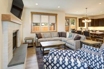 Large corner grey sofa with pillows and blankets and rustic coffee table with fireplace.