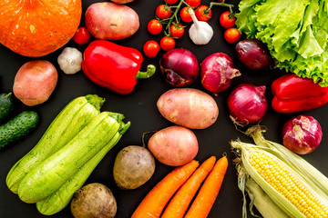 Fresh vegetables still life. Potato, cucumber, beet carrot, greenery on black background top-down