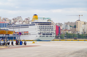 Cruise ship or cruiseship liner in port of Piraeus of Athens, Greece with city skyline and...