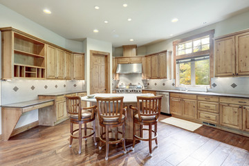 Bright wooden large kitchen interior with island with three chairs and white grey backsplash.