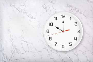 White round wall clock on white natural marble background. Ten o'clock, 10 a.m. or 10 p.m.