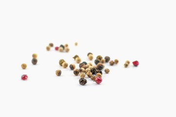 Red, green and black peppercorns or balls mixed isolated on a white background.
