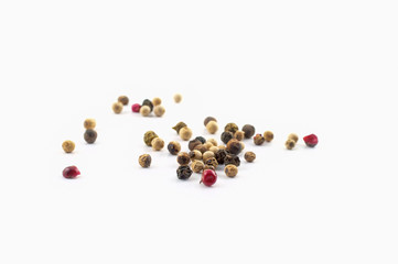 Red, green and black peppercorns or balls mixed isolated on a white background.