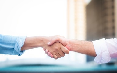 Fototapeta na wymiar Two roll up shirt sleeves businessman shaking hands agreement with blurred building background, successful business collaboration and teamwork,Team agreement in hands gesture communication