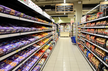 Products on shelves in chain supermarket. Chocolate and coffee on display for sale in hypermarket....
