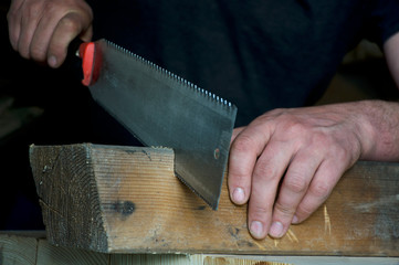 carpenter sawing a wooden beam on the desktop