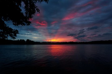 Beautiful evening sunset with red sun rays on a dark blue sky, the river Daugava in the foreground, Latvia