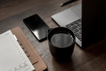 workplace composition with laptop, smartphone, notepad, coffee and pen