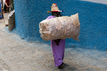 Local woman carrying huge bag in the city of  Chefchaouen,Morocco.