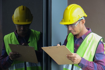 Worker, inspector, engineer or auditor is checking building structure around window with checklist...