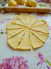 Rolled out dough cut into triangles. Behind it is a rolling pin and three balls of dough. Homemade cooking. Bulgarians put chocolate on the trinagles, roll in and then it is ready for baking.