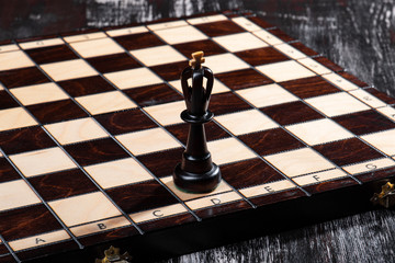 
wooden chess pieces with a playing board against a dark background