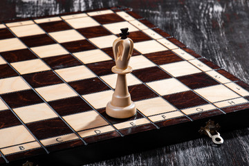
wooden chess pieces with a playing board against a dark background